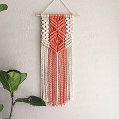 an orange and white wall hanging next to a plant