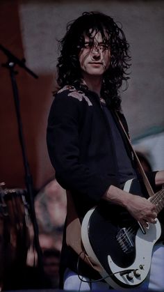 a man with long hair playing an electric guitar