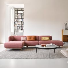 a living room with a pink couch and coffee table in front of bookshelves