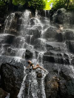 a woman laying on top of a waterfall