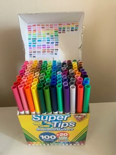 a box filled with lots of different colored crayon pens on top of a table