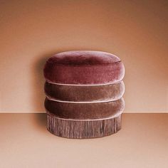 three round cushions on top of each other in front of a pink wall and floor