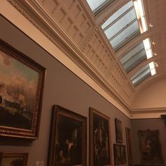 an art gallery with paintings on the wall and skylight above it in a building