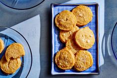 some cookies are on a blue plate next to plates with silverware and glass dishes