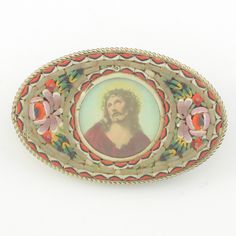 an oval brooch with a painting of jesus in the center and flowers around it