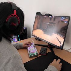 a person sitting at a desk with a keyboard and headphones on, playing a video game