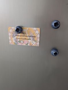 there are three blue knobs on the door of this refrigerator that has a note attached to it