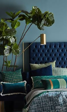 a bedroom with blue walls and green plants on the headboard, bed linens and pillows