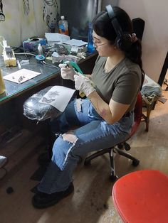 a woman sitting at a desk with headphones on and holding a toothbrush in her hand