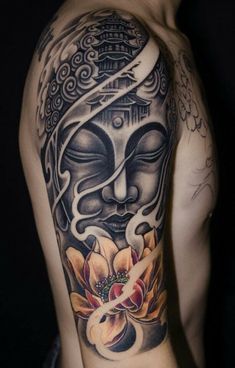 a man with a buddha tattoo on his arm and shoulder, holding a flower in front of him