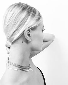 a woman with a tattoo on her left side of her neck and behind her ear