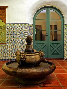 a fountain in the middle of a room with tiled walls and doors on either side