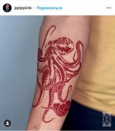 an octopus tattoo on the arm of a man's left arm, with red ink