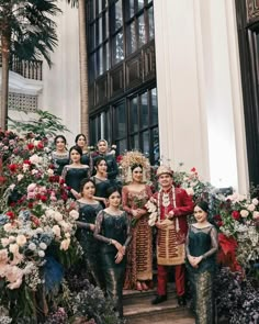 a group of women standing next to each other in front of flowers