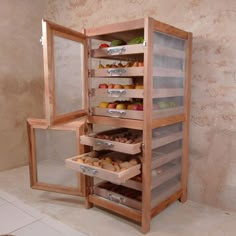 an open wooden cabinet with drawers filled with fruits and pastries on the bottom shelf