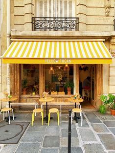 yellow and white striped awning over tables in front of a building