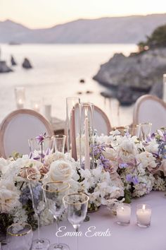 the table is set with flowers and candles for an elegant wedding reception at the beach