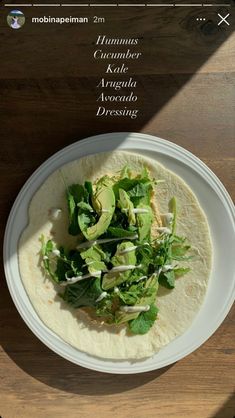 a white plate topped with a taco covered in lettuce and avocado