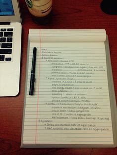 a notepad sitting on top of a wooden desk next to a laptop computer