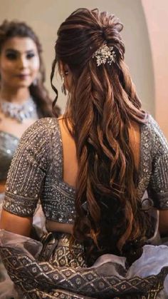 a woman with long hair sitting in front of a mirror