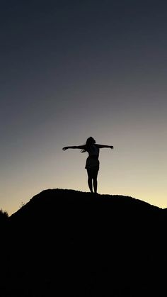 a person standing on top of a hill with their arms outstretched