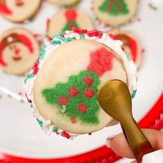 a person is holding a cookie decorated like a christmas tree with red, green and white icing