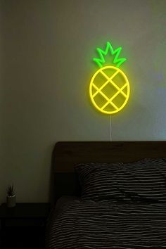 a bed with a black and white striped comforter next to a neon green neon pineapple sign