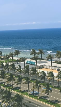 an aerial view of the ocean with palm trees in front of it and a hotel sign