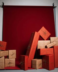 a pile of wrapped presents sitting on top of a red floor next to a wall