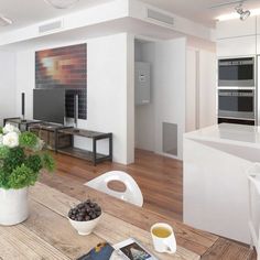 an open concept kitchen and living room with wood flooring, white walls and cabinets