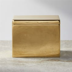 a gold metal box sitting on top of a white table next to a gray wall