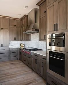 a kitchen with wooden cabinets and stainless steel appliances in the center, along with wood flooring