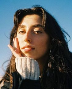 a close up of a person wearing a jacket and holding her hand near her face