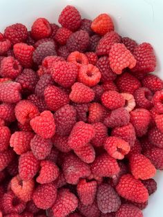 raspberries are in a white bowl on the table