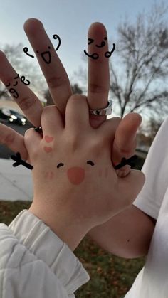 someone has drawn faces on their fingers to spell out the word'i love you '