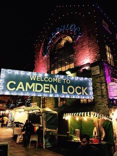 a sign that reads, welcome to camden lock at night in front of a brick building