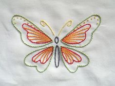 an embroidered butterfly is shown on a white shirt with orange and green trimmings