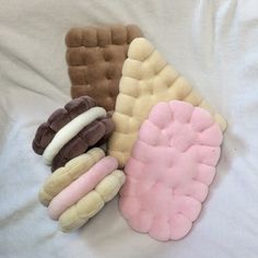 three different types of stuffed animals laying on top of a white bed sheet, one is pink and the other is brown