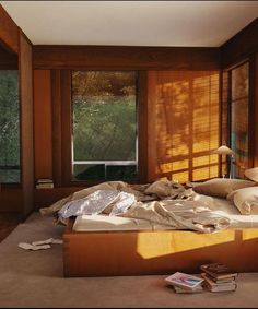 an unmade bed sitting in a bedroom next to a window with the sun shining through it