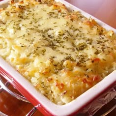 a casserole dish with cheese and herbs in it sitting on a wooden table