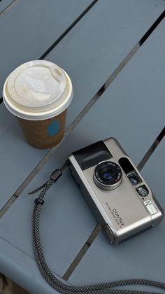 an old camera and a cup of coffee sit on a blue table with a metal chain