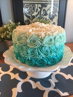 a cake that is sitting on top of a white plate with blue and green frosting