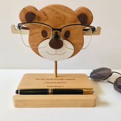 a wooden bear head with glasses on top of it and a pen next to it