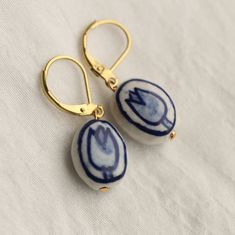 pair of blue and white ceramic earrings on gold earwires with hook closures