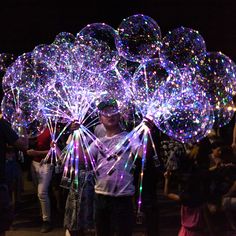 a man standing in front of a group of people holding up large bubbles that look like fireworks