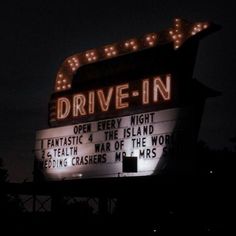 the drive - in sign is lit up at night