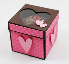 a small pink box with hearts on the lid and window in the shape of a heart