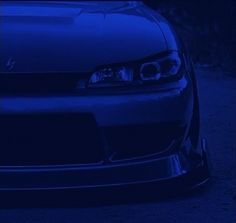 the front end of a blue car at night