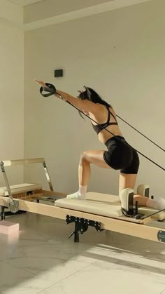 a woman is doing exercises on an exercise board while standing on one leg and holding a jump rope in the other hand