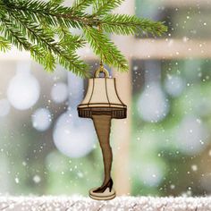 a christmas ornament hanging from a tree in front of a window with snow falling on it